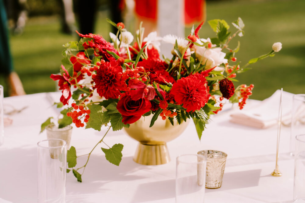 Gold compotes filled with summer flowers placed on blush linens