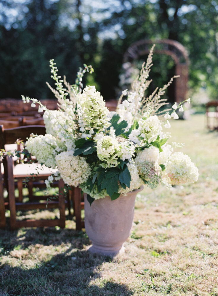 Back of the wedding ceremony aisle flowers. Terra cotta urns filled with late summer flowers
