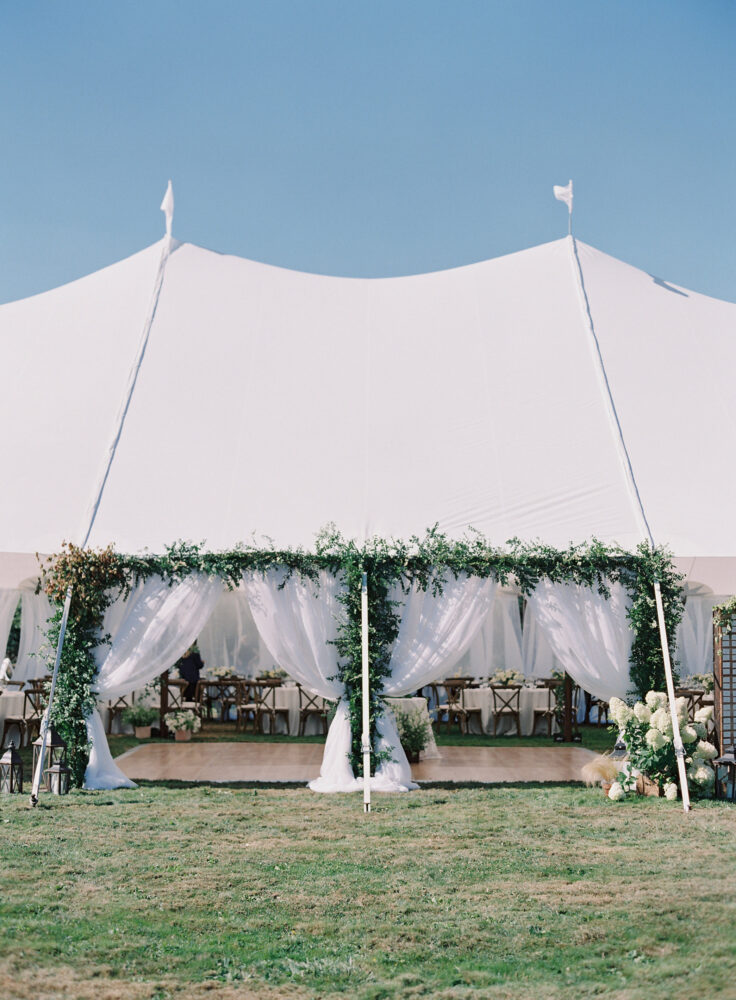 Sail cloth tent entrance. Decorated with an installation of greenery.
