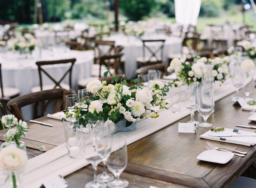 Wood farm tables decorated with a ix of centerpieces and bud vases