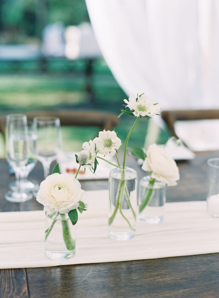 Farm table details. Bud vases filled with white flowers
